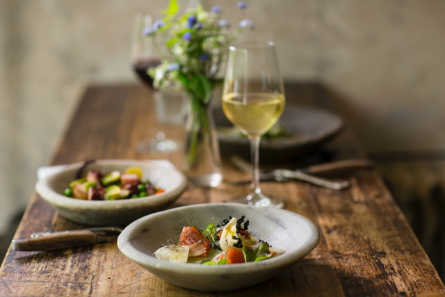 Beautifully plated food on a rustic wood table with a glass of white wine